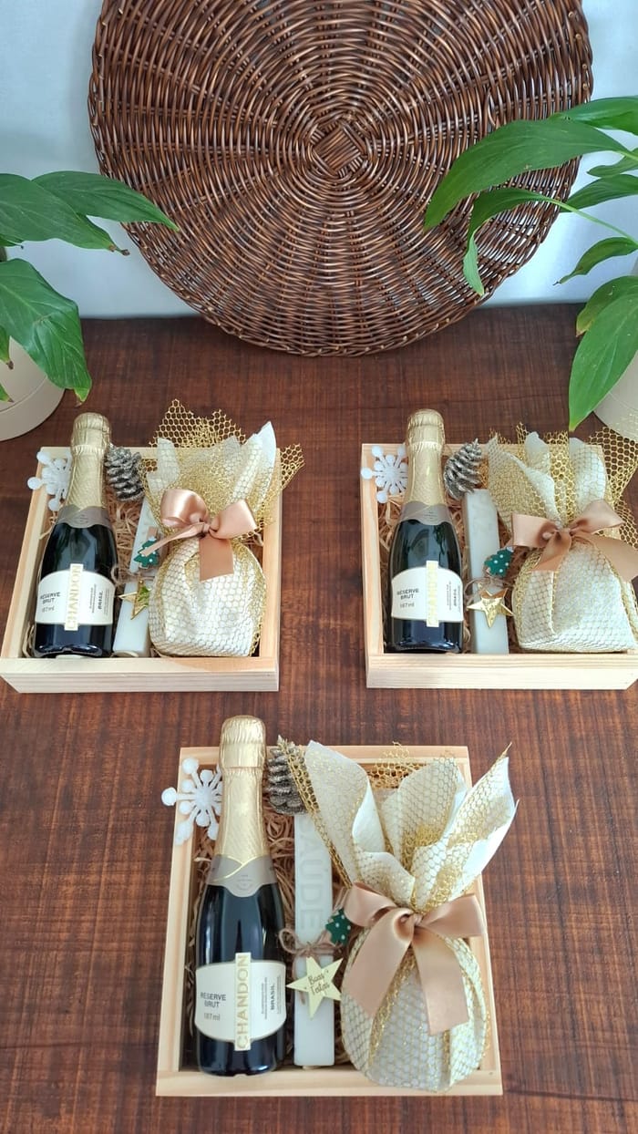 Bandejas de madeira com espumante, panetone embrulhado em dourado e vela decorativa de Boas Festas